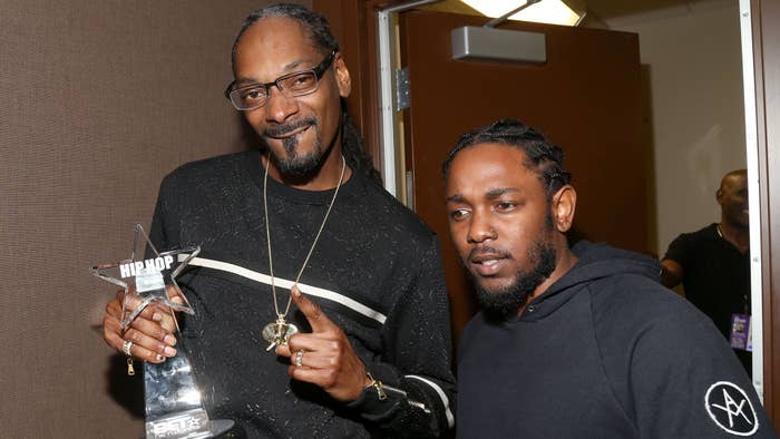 Snoop Dogg holds a Hip Hop award and gestures while standing next to Kendrick Lamar, who is wearing a casual hoodie