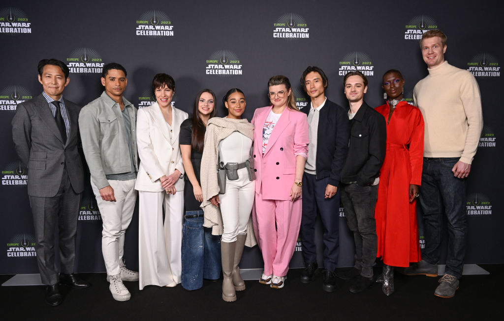 Group of people including Daisy Ridley, Hayden Christensen, and Rosasario Dawson on a Star Wars Celebration red carpet, in stylish event attire