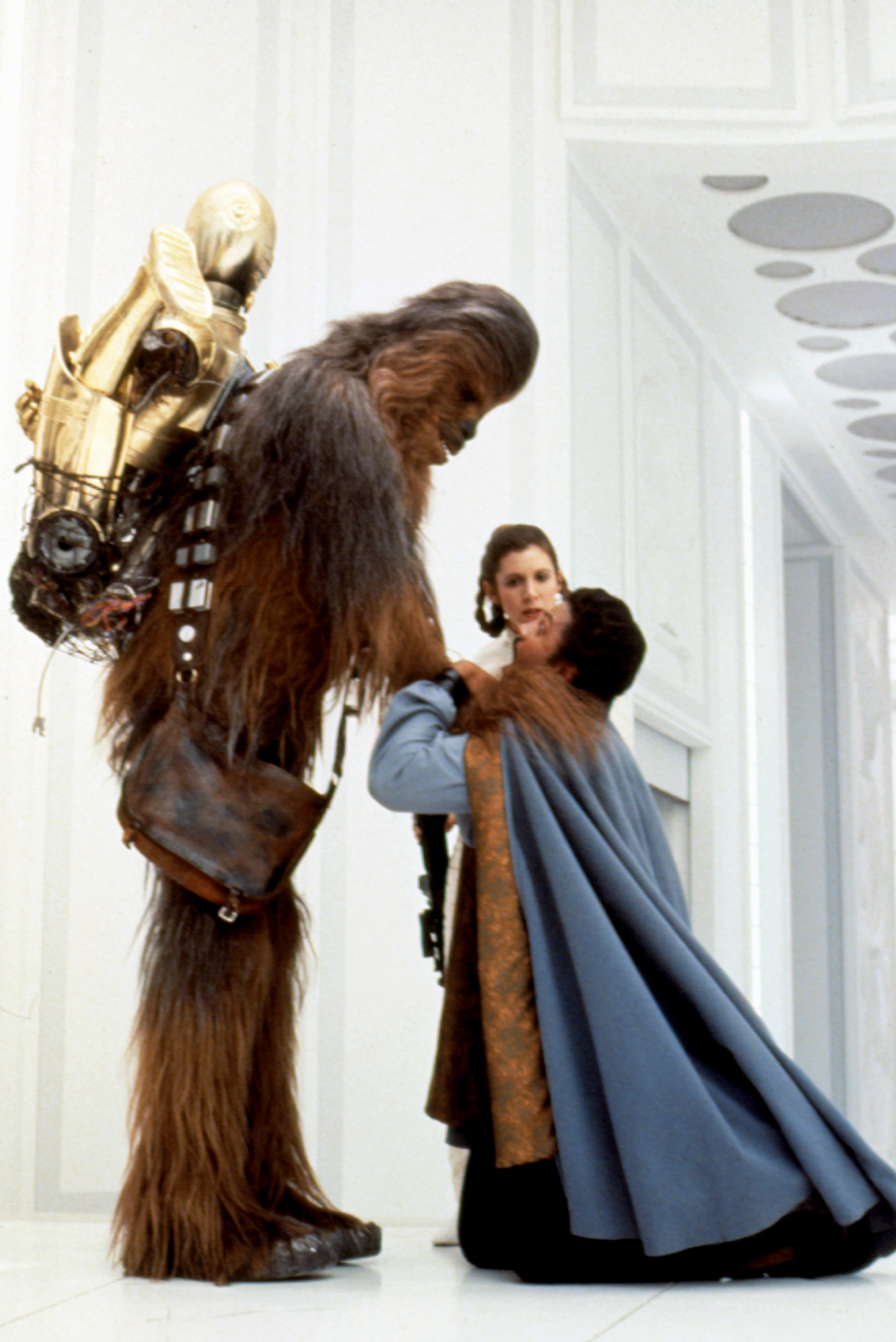Chewbacca holding C-3PO on his back while comforting Princess Leia and Lando Calrissian in a scene from Star Wars