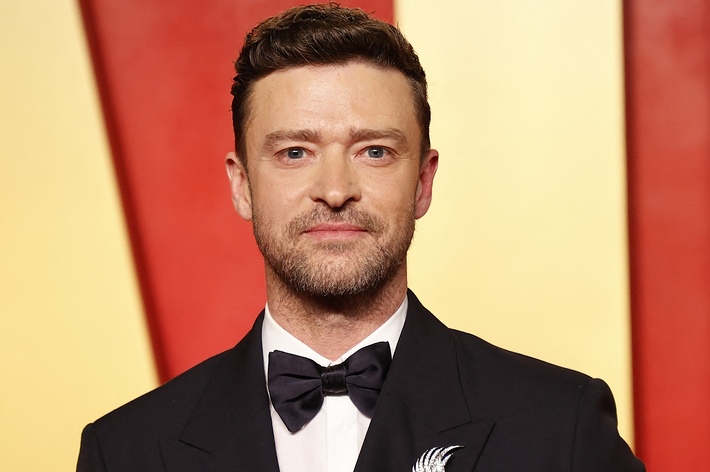 Justin Timberlake poses in a tuxedo with a bow tie on a red carpet