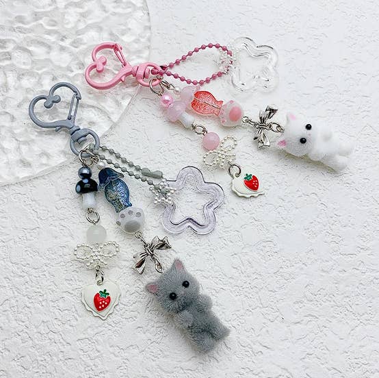 Llavero con figuras de gatos esponjosos y adornos colgantes en forma de fresas, lazos, peces y cuentas decorativas