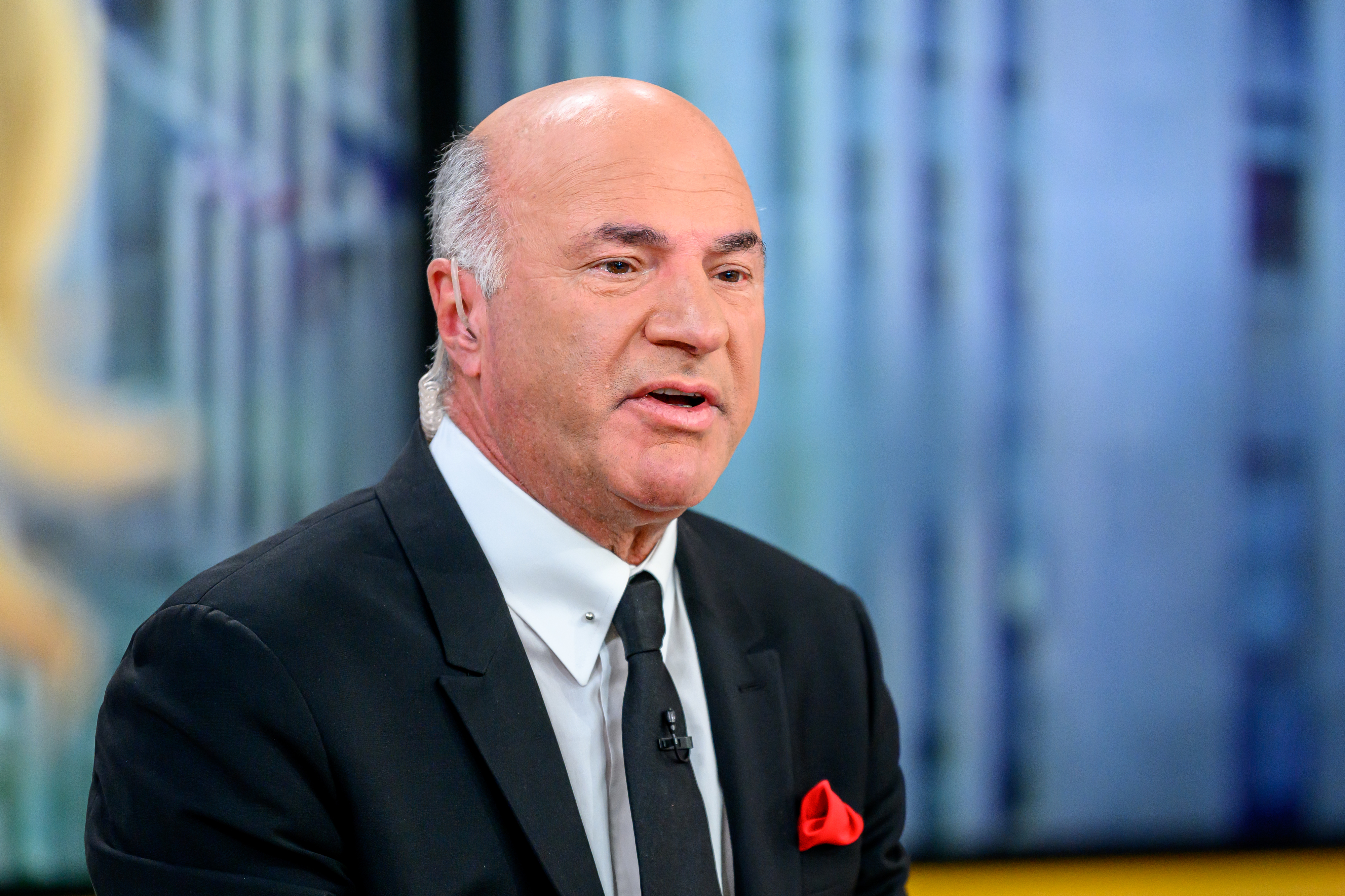 Kevin O'Leary in a business suit, speaking on a television set