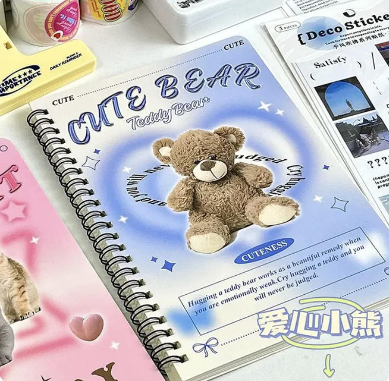 Cuaderno espiralado con portada de osito de peluche llamado "Cute Bear". frases sobre ternura. Otros artículos de papelería alrededor del cuaderno