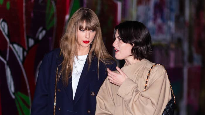 Taylor Swift and Phoebe Bridgers are seen walking together. Taylor Swift is wearing a navy jacket, and Phoebe Bridgers is in a beige coat with a black bag