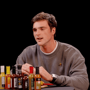 Jacob Elordi, wearing a casual crew-neck sweatshirt, sits at a table with various hot sauces in front of him. He says &quot;hell no, man, absolutely not me, man&quot;
