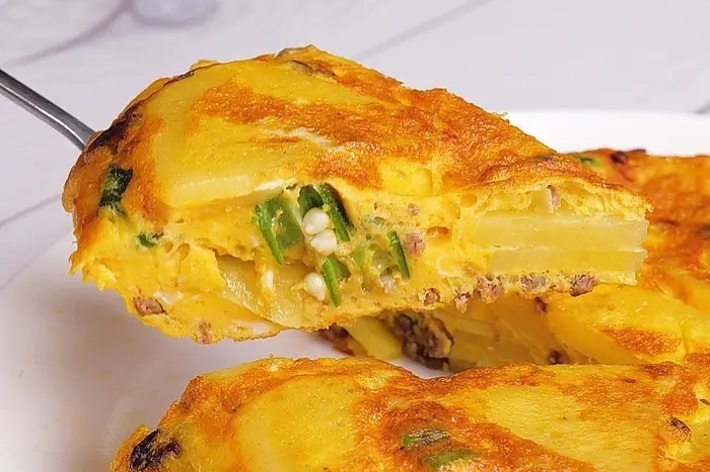 オムレツの一部をフォークで持ち上げた写真。ジャガイモと野菜が中に入っている。