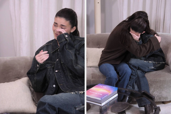 Kylie Jenner and Kendall Jenner sitting on a couch; Kylie is emotional and Kendall is comforting her with a hug. Both are wearing casual outfits
