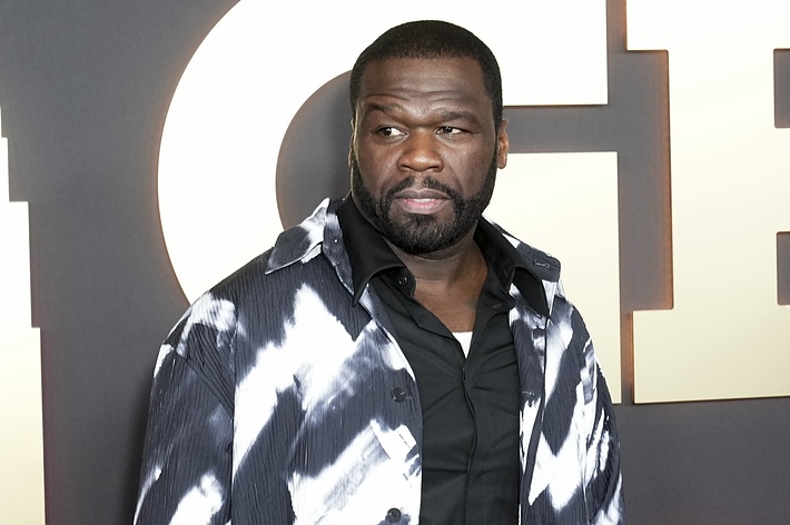 50 Cent on the red carpet wearing a black and white patterned jacket over a black shirt