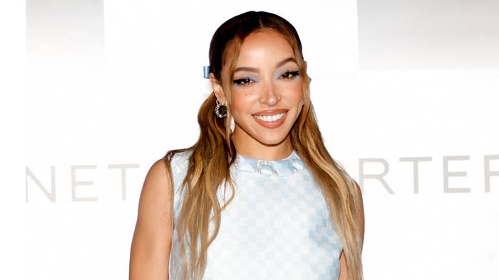 Tinashe, wearing a sleeveless patterned dress, smiles while posing at a music event