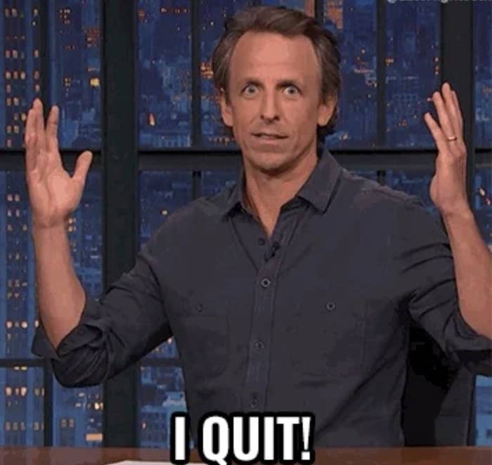 Seth Meyers is sitting at a desk on a late-night show set with hands raised, accompanied by a caption, "I QUIT!"