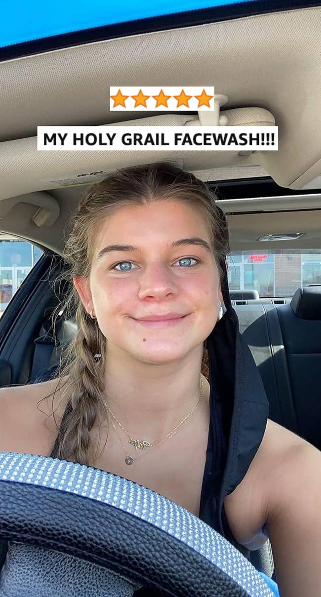A reviewer with a braided hairstyle sits successful a car, wearing a necklace and a half-removed look mask. There are disposable store signs successful the inheritance extracurricular the car