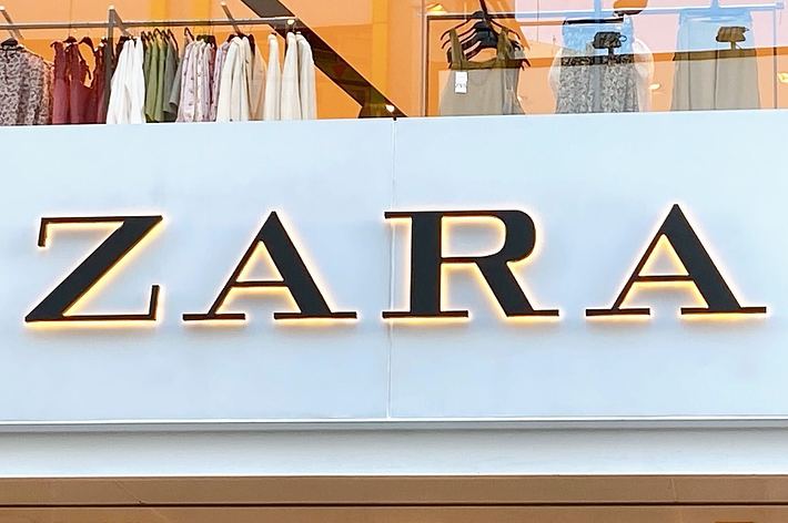 ZARA store exterior with large sign reading “ZARA” and a display of clothes visible through the windows above
