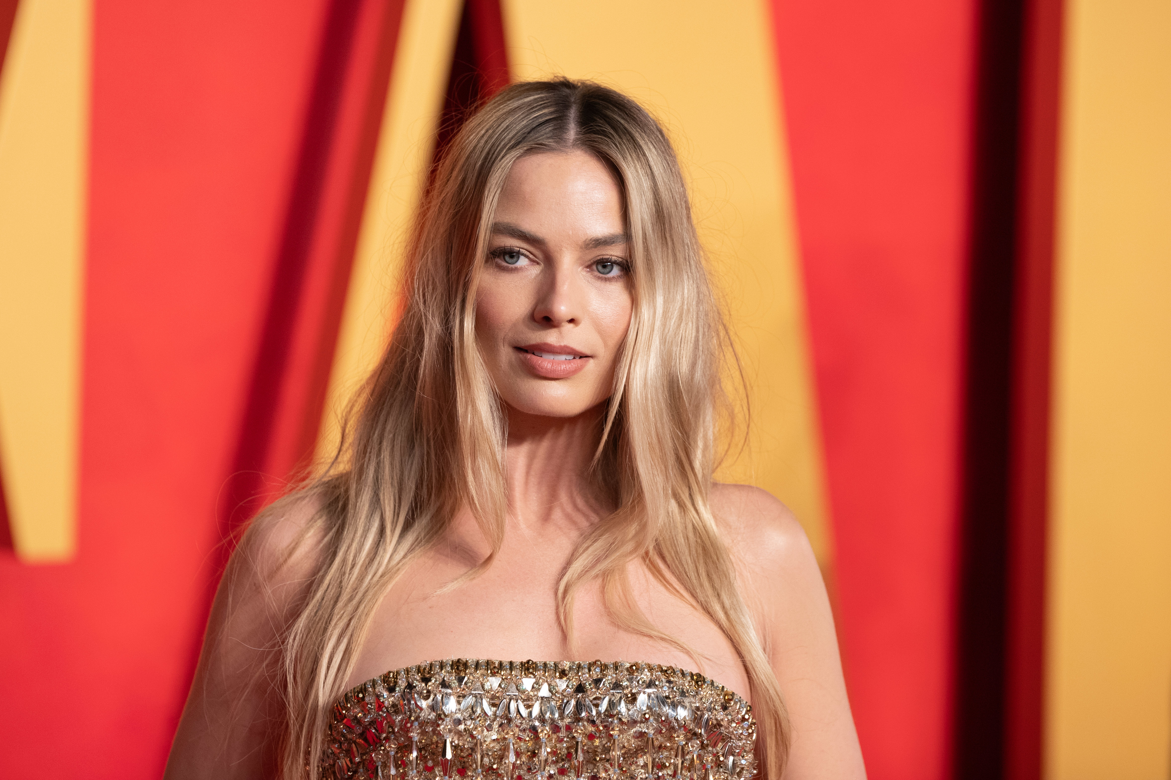Margot Robbie on the red carpet wearing a strapless, sequined dress