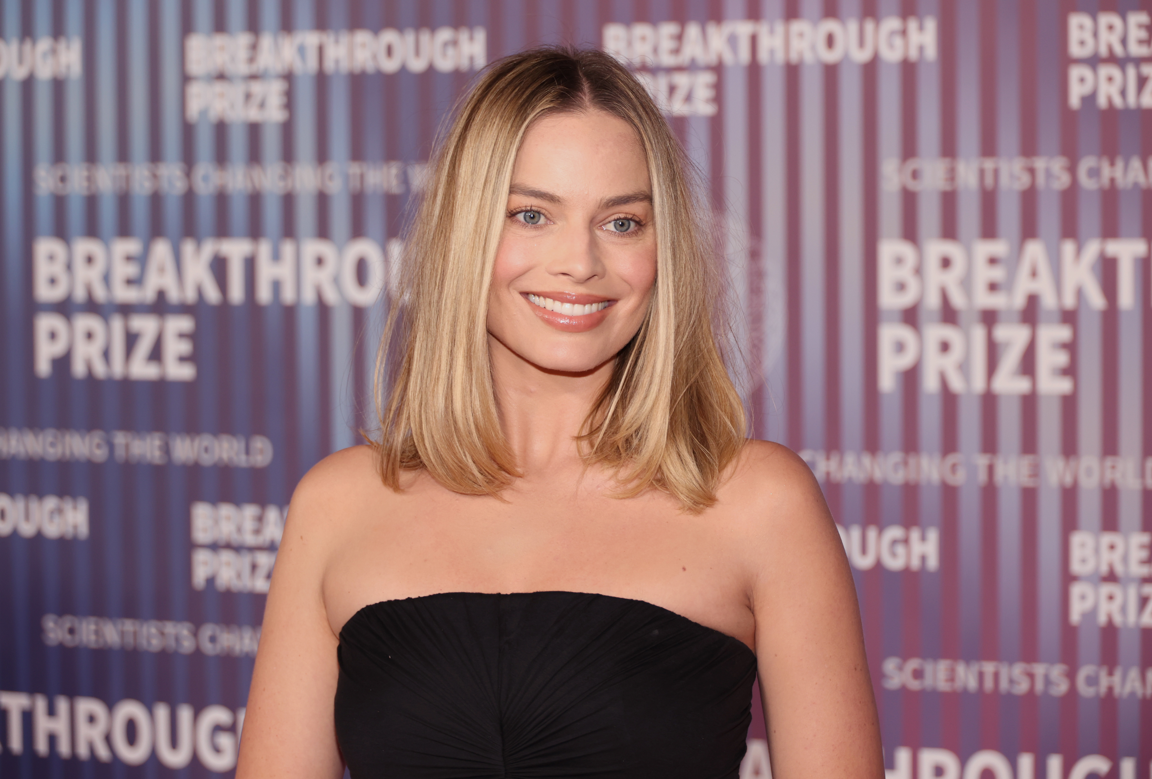 Margot Robbie at the Breakthrough Prize event, wearing a strapless dress World"