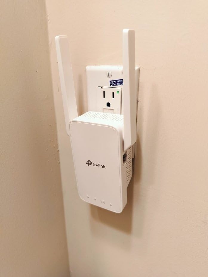 TP-Link Wi-Fi Range Extender plugged into an electrical outlet on a beige wall