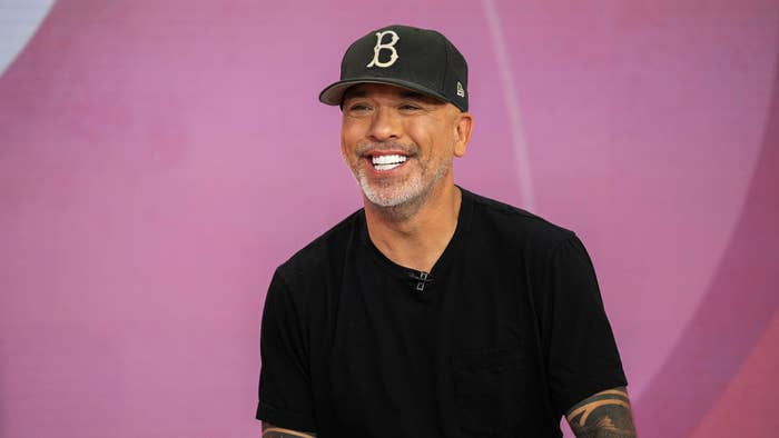 A man is smiling and wearing a dark cap with a &quot;B&quot; on it and a dark T-shirt