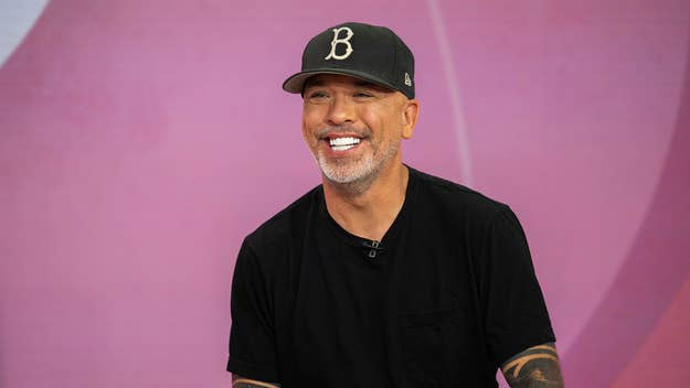 A man is smiling and wearing a dark cap with a "B" on it and a dark T-shirt