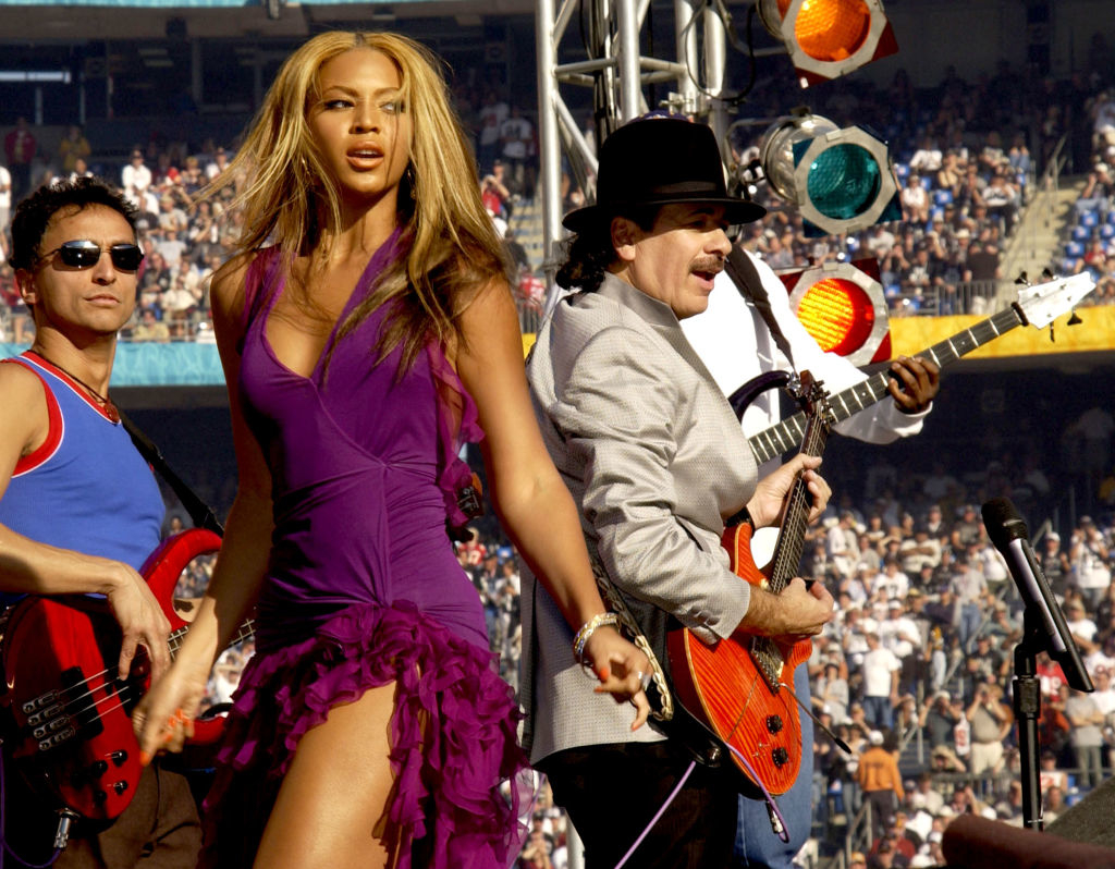 Beyoncé performs on stage with Carlos Santana and other musicians during a live concert at a stadium