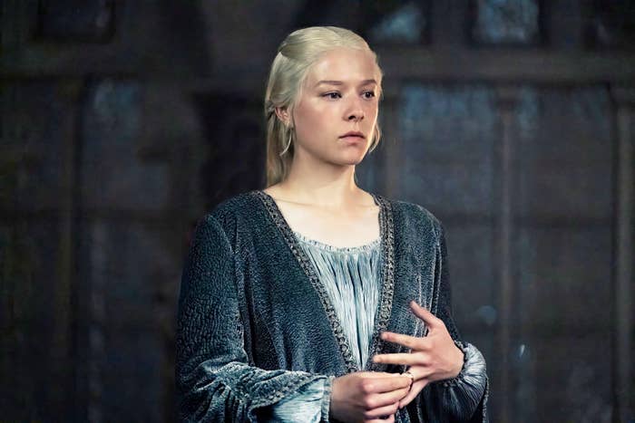 Emma D'Arcy as Rhaenyra Targaryen from "House of the Dragon" wearing a medieval-style robe in an indoor scene