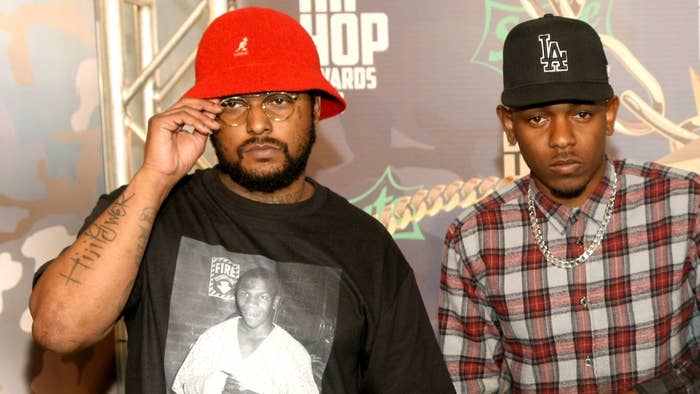 ScHoolboy Q and Kendrick Lamar at a Hip Hop Awards event. ScHoolboy Q is wearing a red hat and a graphic t-shirt, while Kendrick Lamar is in a plaid shirt and LA cap