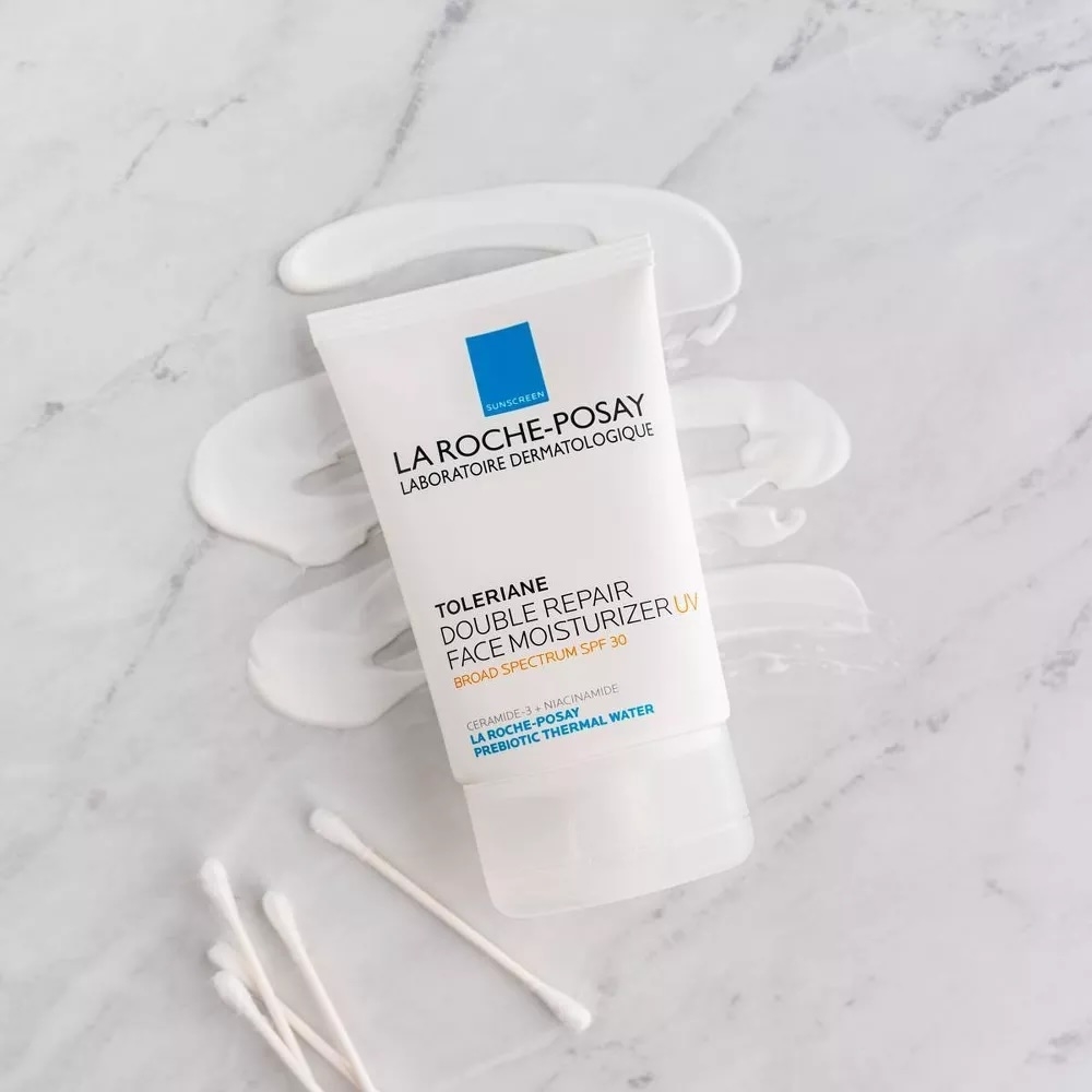 La Roche-Posay Toleriane Double Repair Face Moisturizer with UV SPF 30, tube on a marble surface with swipes of the product and three cotton swabs beside it