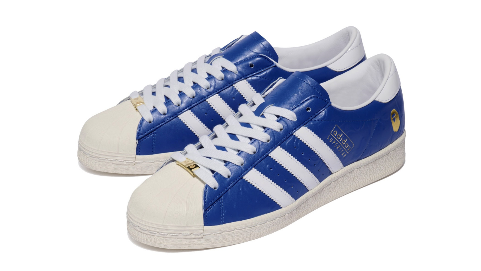 Blue and white Adidas Superstar sneakers with gold accents on the laces and logo