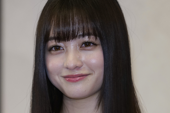 橋本環奈がトロフィーを持って微笑む姿。刺繍の入った衣装を着用。