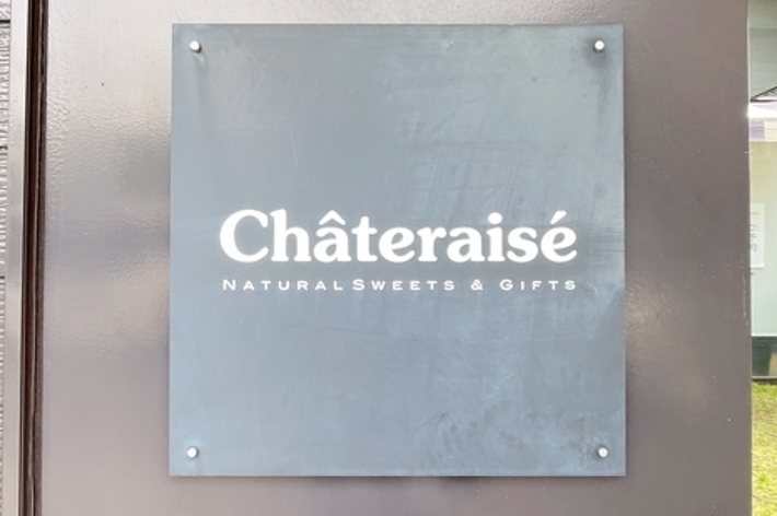 建物の外壁に掲示された「Chateraise NATURAL SWEETS &amp; GIFTS」の看板。