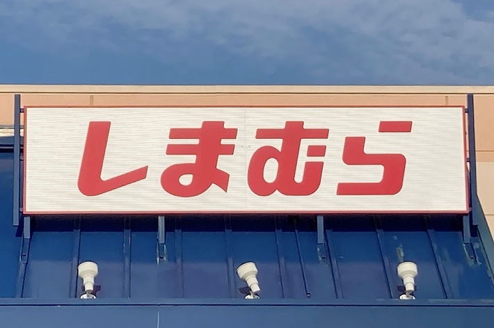The image shows the storefront of a Shimamura retail store with a large sign featuring the store’s name in Japanese characters