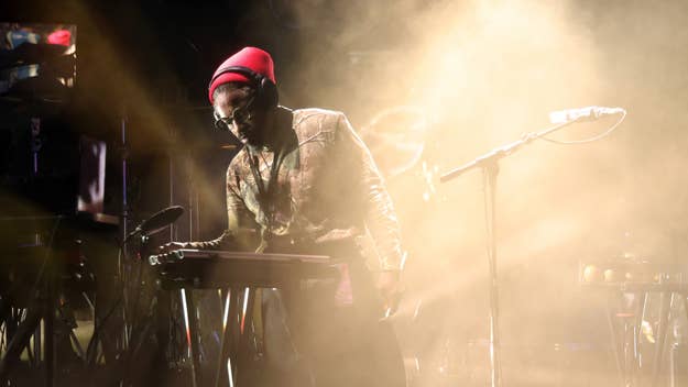 3 Stacks performing on stage, playing a keyboard and wearing a beanie and glasses amidst bright stage lighting