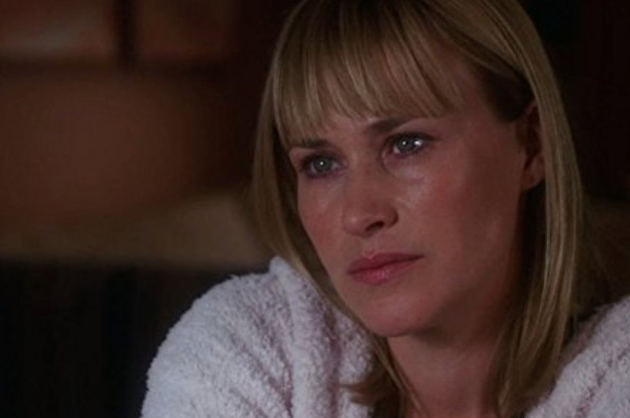 Patricia Arquette in a close-up shot, looking solemn while wearing a white textured robe