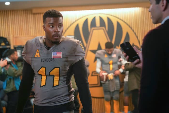 Daniel in a "Condors" football uniform with number 11 is being interviewed in a locker room in a scene from All American