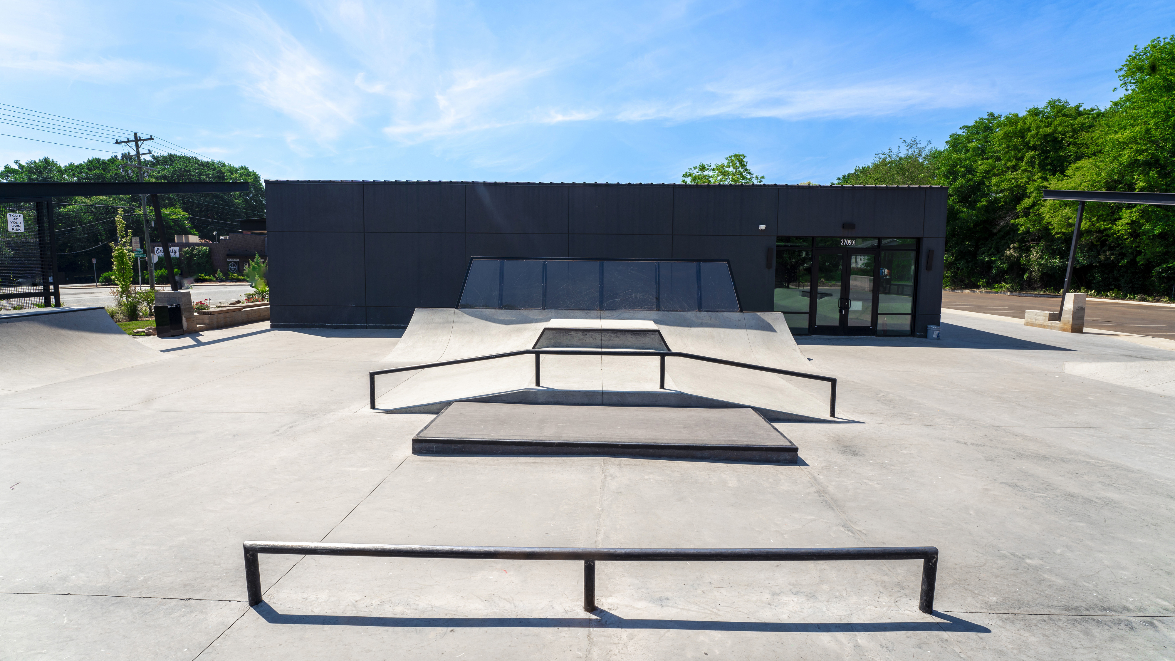A modern skate park featuring various ramps and railings in an outdoor setting with a building in the background