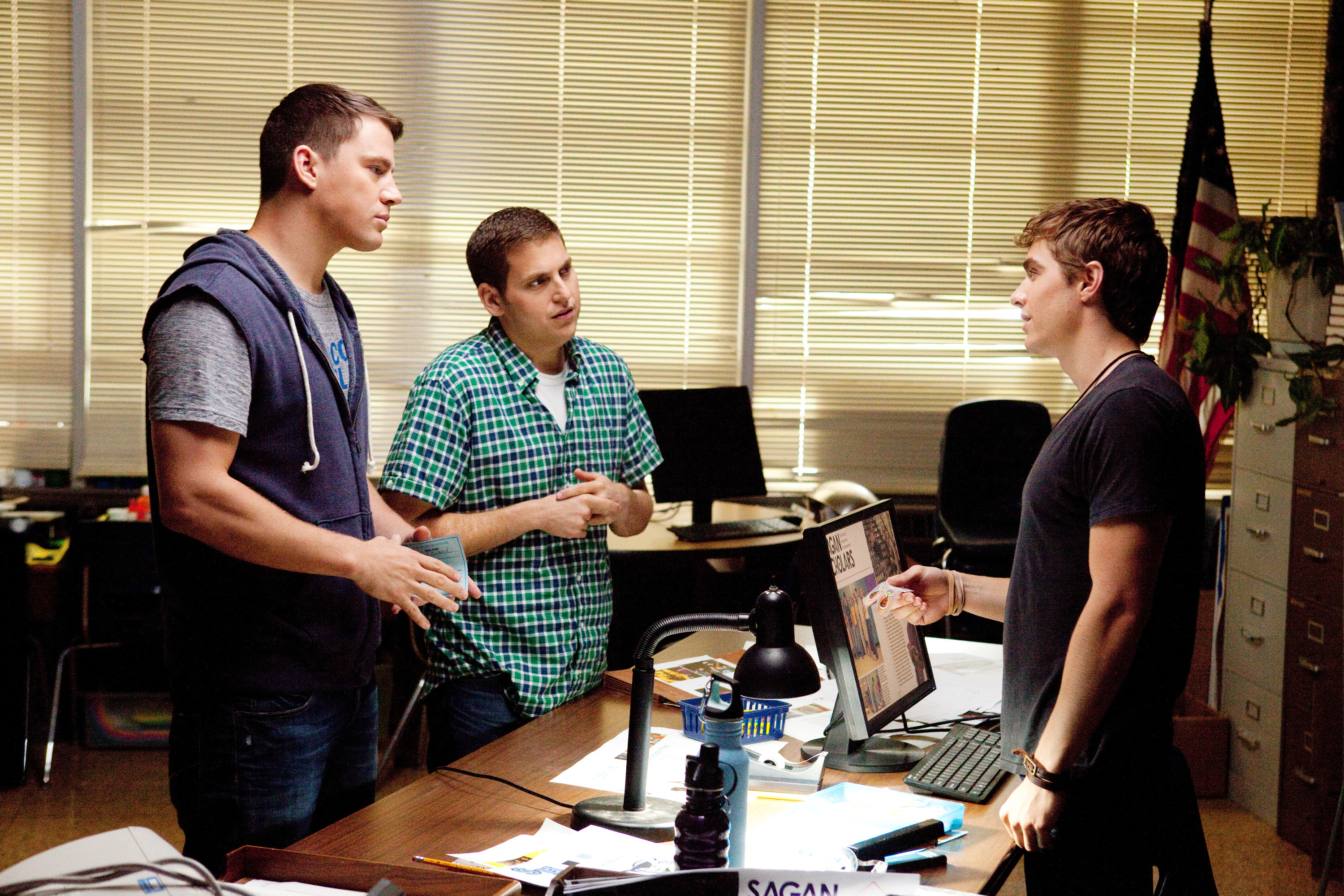 Channing Tatum, Jonah Hill, and Dave Franco stand around an office desk discussing something