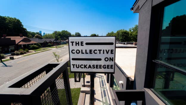 Sign for The Collective on Tuckaseegee, viewed from a second-floor balcony, overlooking a quiet street with houses and trees