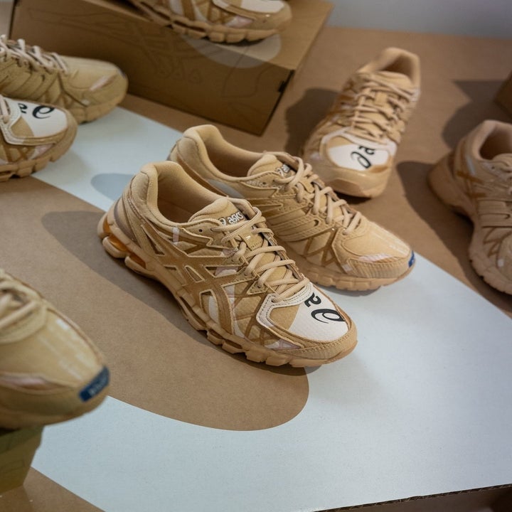 Various pairs of beige sneakers with intricate designs arranged artistically on a floor and cardboard boxes