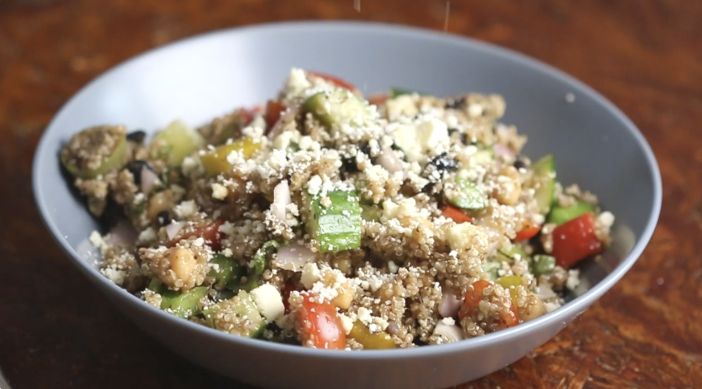 A bowl of quinoa salad with diced vegetables and crumbled feta cheese