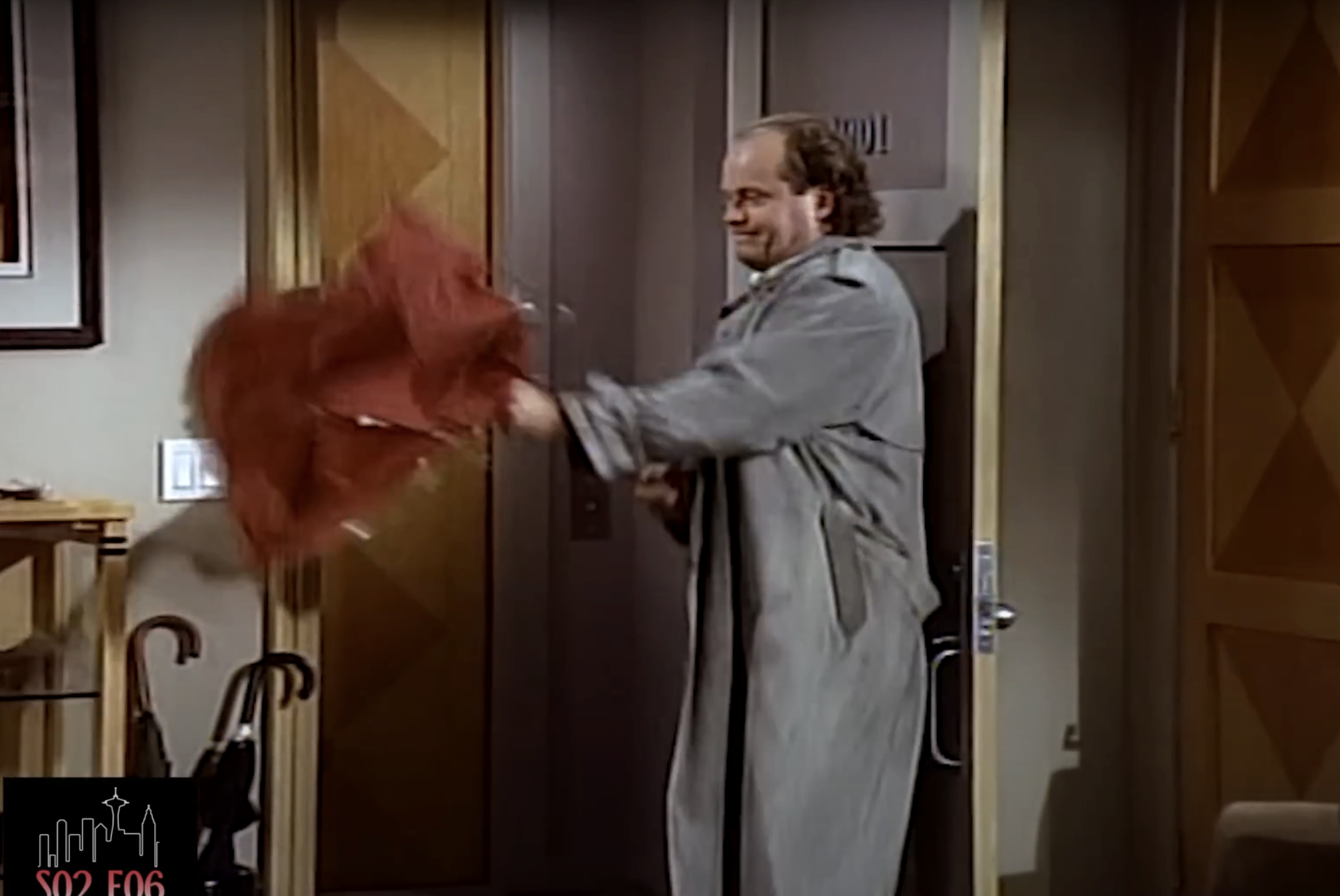 Niles Crane from "Frasier" in a comedic scene, struggles with an umbrella in an apartment doorway