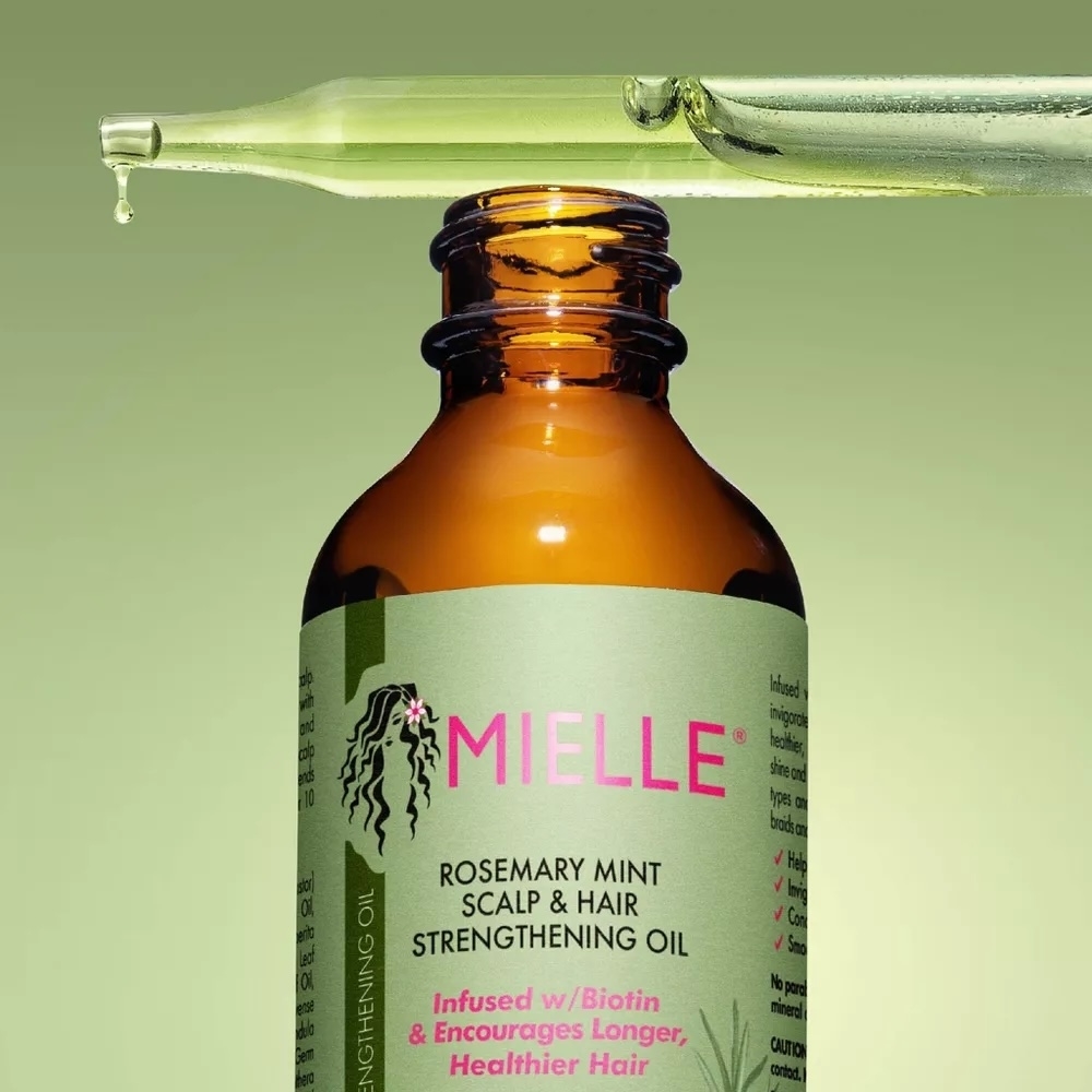 Mielle Rosemary Mint Scalp &amp; Hair Strengthening Oil bottle with a dropper releasing oil. Promoted for healthier, longer hair with biotin