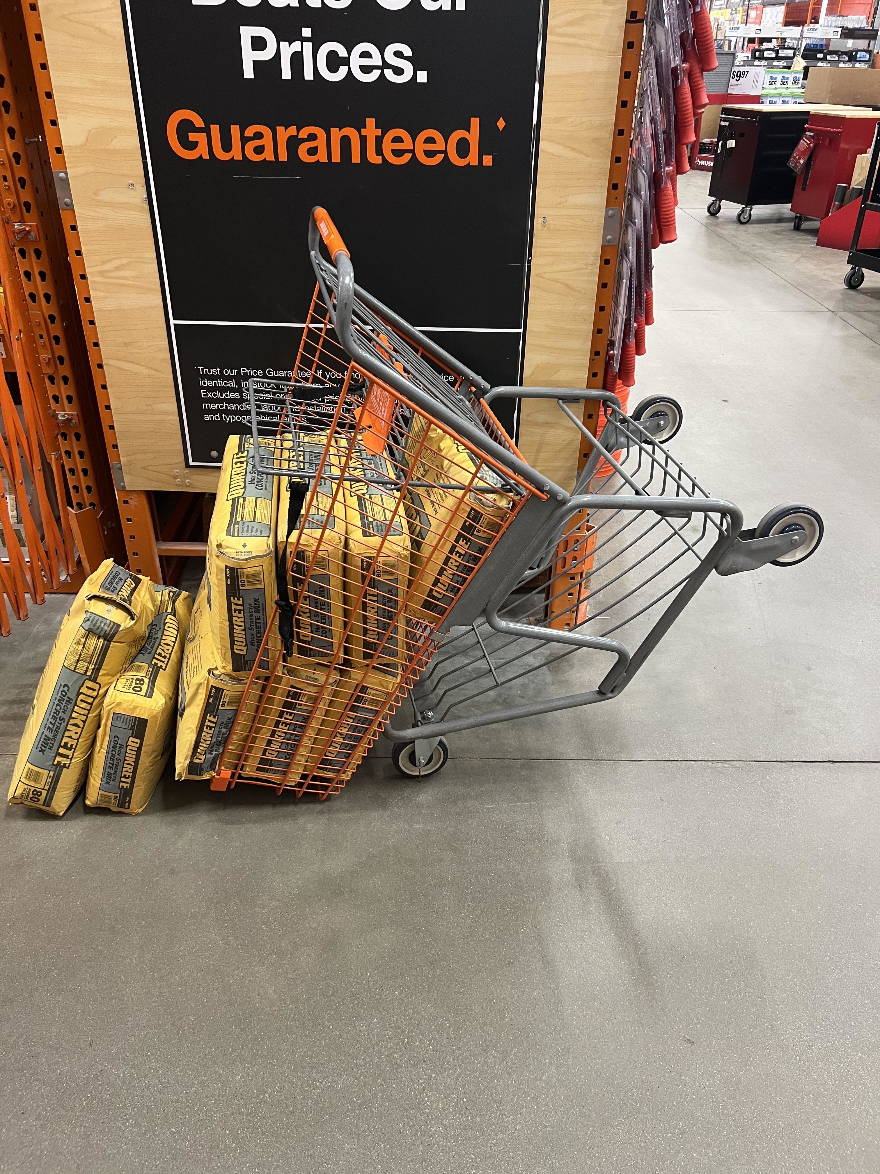Shopping cart tipping over due to being overloaded with bags of concrete mix at a construction supply store