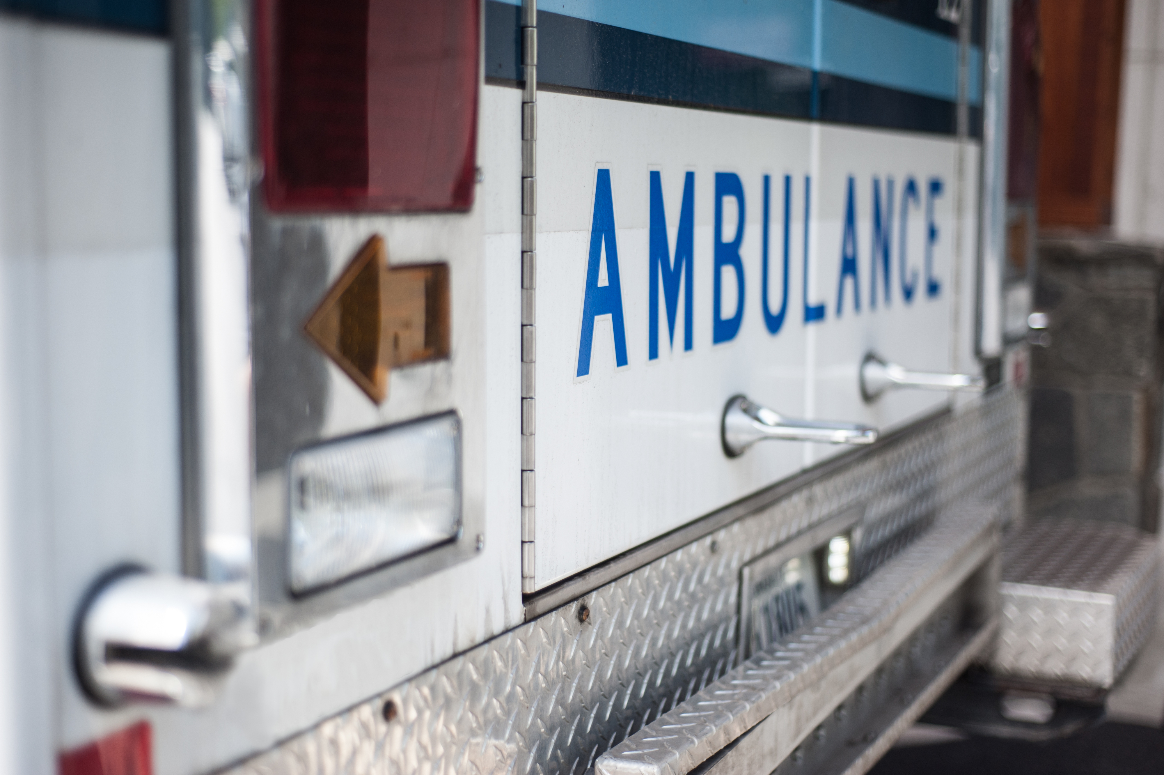 Close-up of an ambulance with visible rear-facing panels and the word &quot;AMBULANCE&quot; on its side
