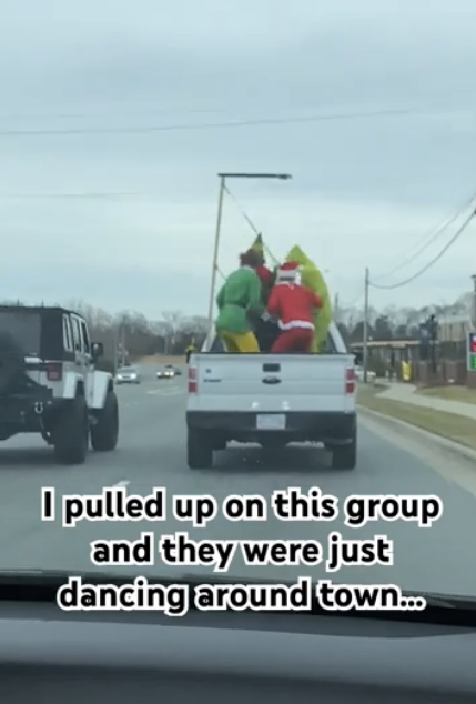 Santa Claus, the Grinch, and a person in a yellow costume dance in the back of a moving pickup truck. Text: "I pulled up on this group and they were just dancing around town…"