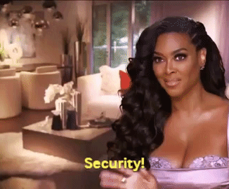 Kenya Moore wearing a glamorous outfit and gesturing while saying &quot;Security!&quot; in a luxurious home setting