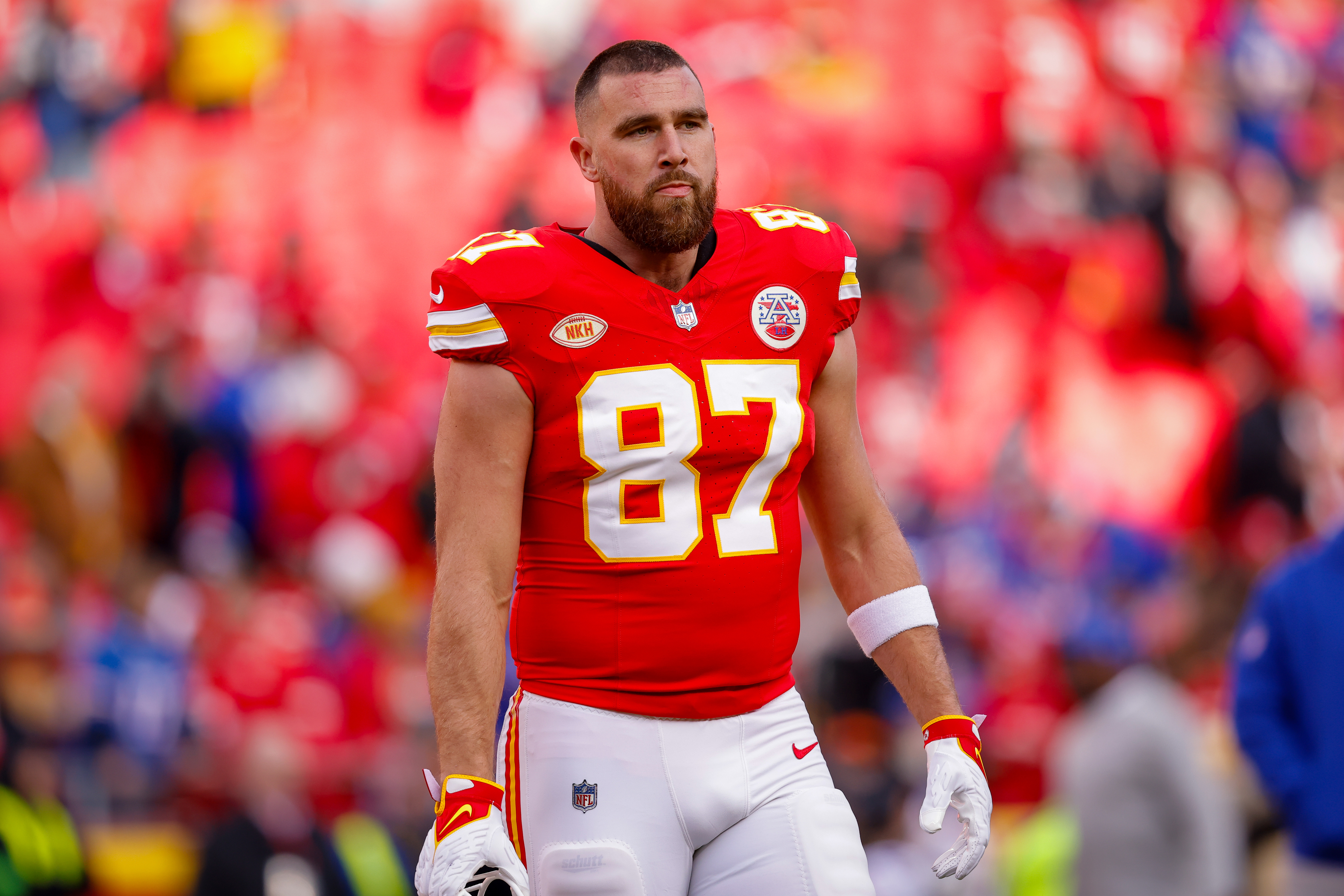 Travis Kelce, wearing an NFL football uniform with number 87, stands on the field during a game
