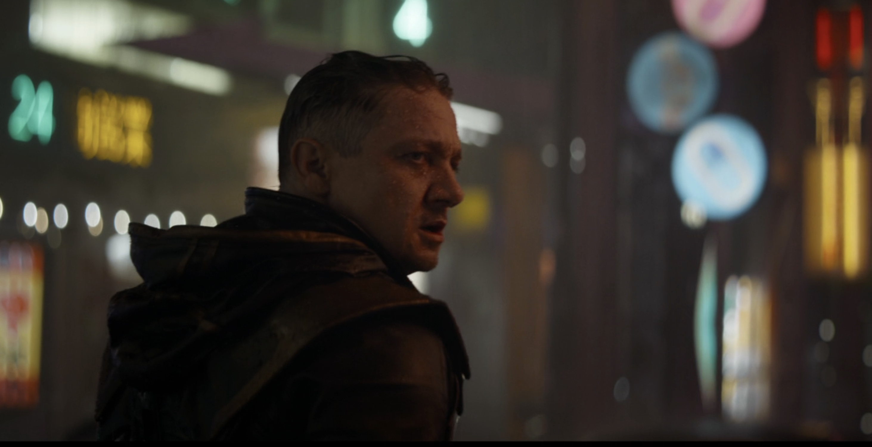 Jeremy Renner as Clint Barton/Hawkeye in a dimly lit, neon street scene