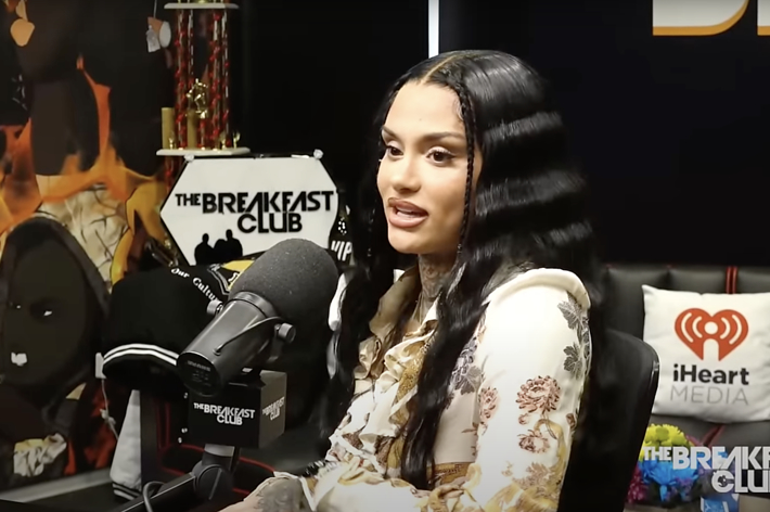 Kehlani speaks into a microphone during an interview at The Breakfast Club radio show. iHeartMedia and The Breakfast Club logos are visible in the background