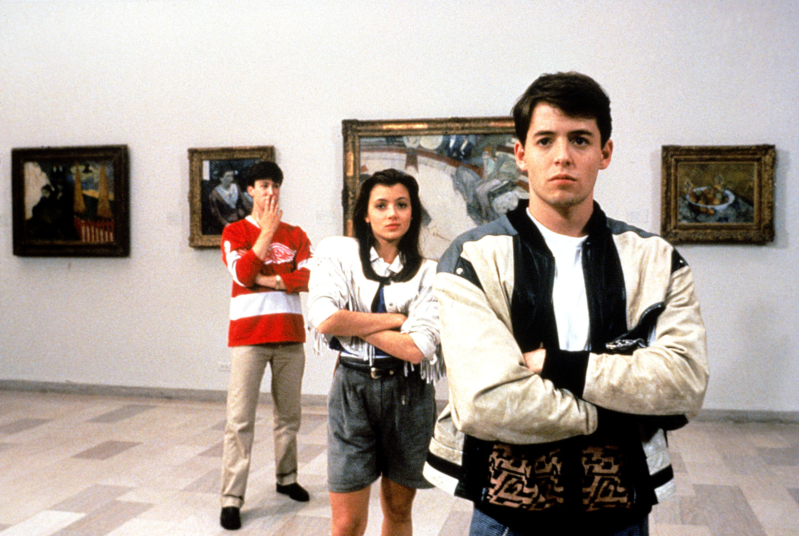 Alan Ruck, Mia Sara, and Matthew Broderick standing in a diagonal line in front of exhibits at an art museum in a scene from &quot;Ferris Bueller's Day Off&quot;