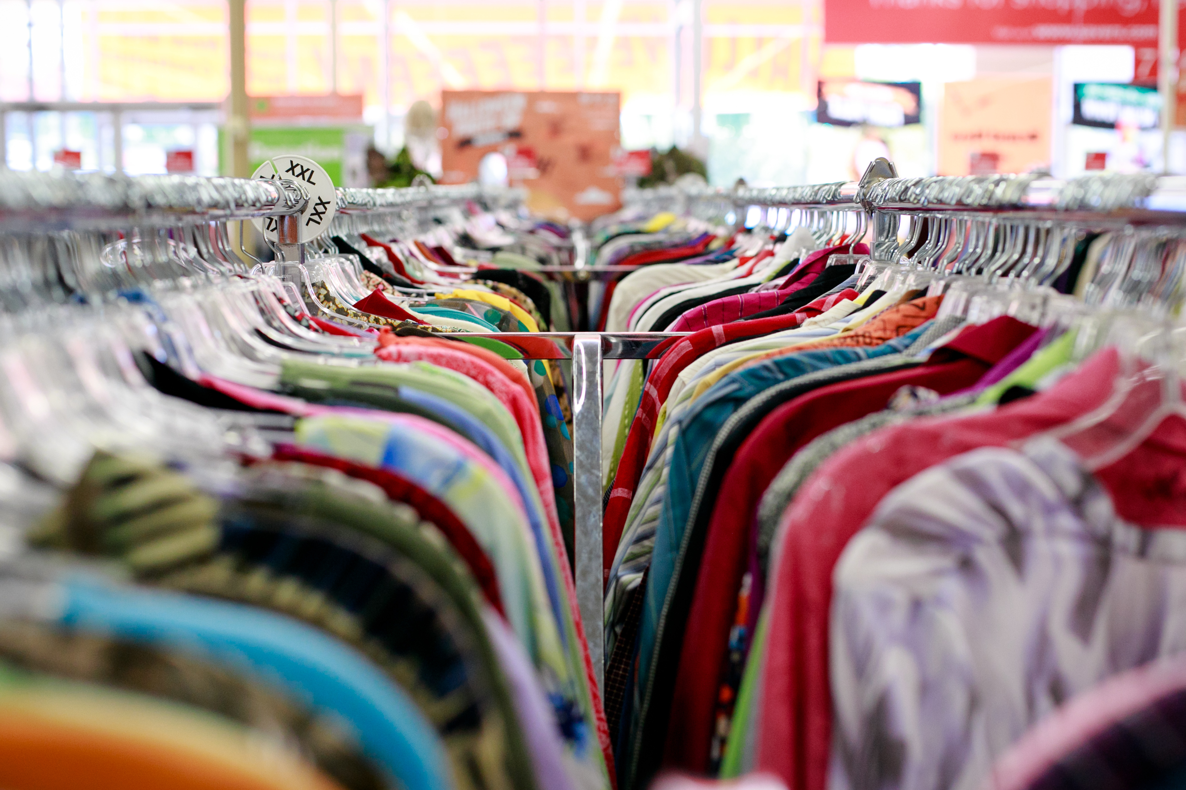 A thrift store clothing rack is filled with a variety of clothing items. The image captures the colorful and diverse selection available in the store