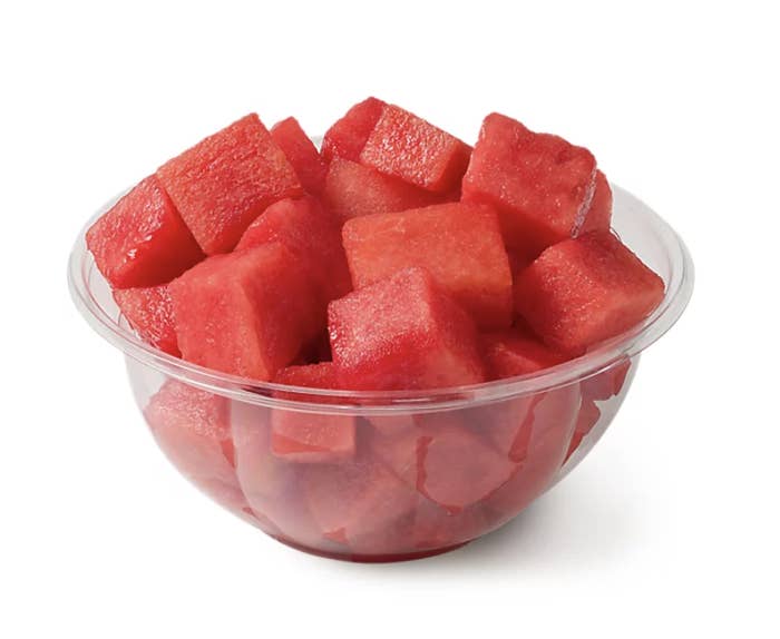 A clear plastic bowl filled with cubed watermelon pieces