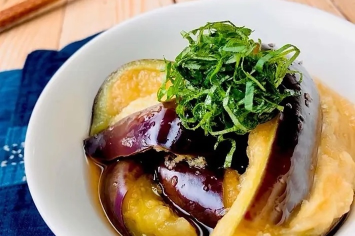 白いボウルに盛りつけられたナスの煮びたしがテーブルに置かれている。